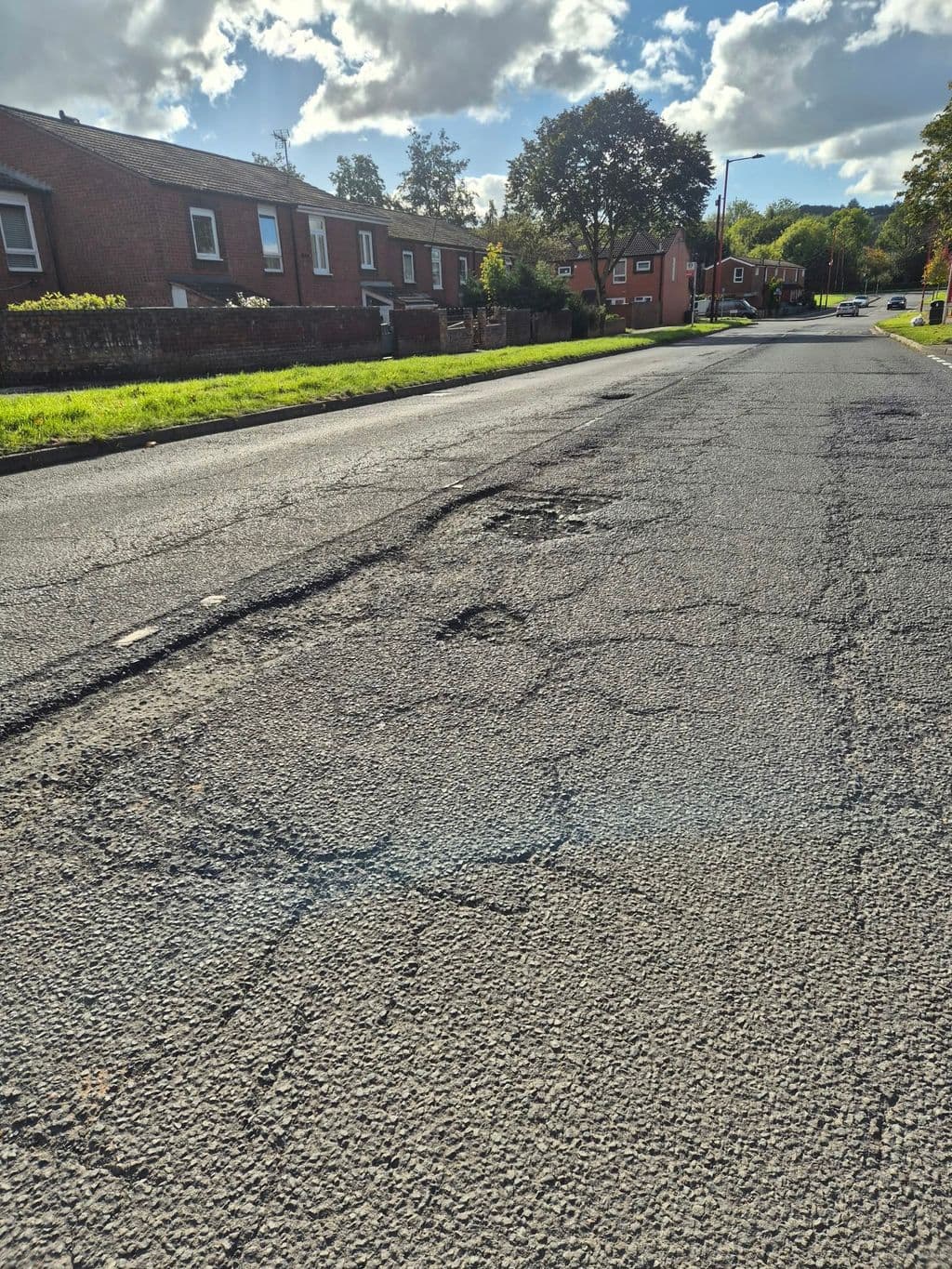 Cracking across the carriageway on Boleyn Road, New Frankley, looking along the road